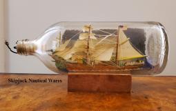 Mid-20th century ship in a bottle diorama depicting a brigantine passing a foreign port and flying t